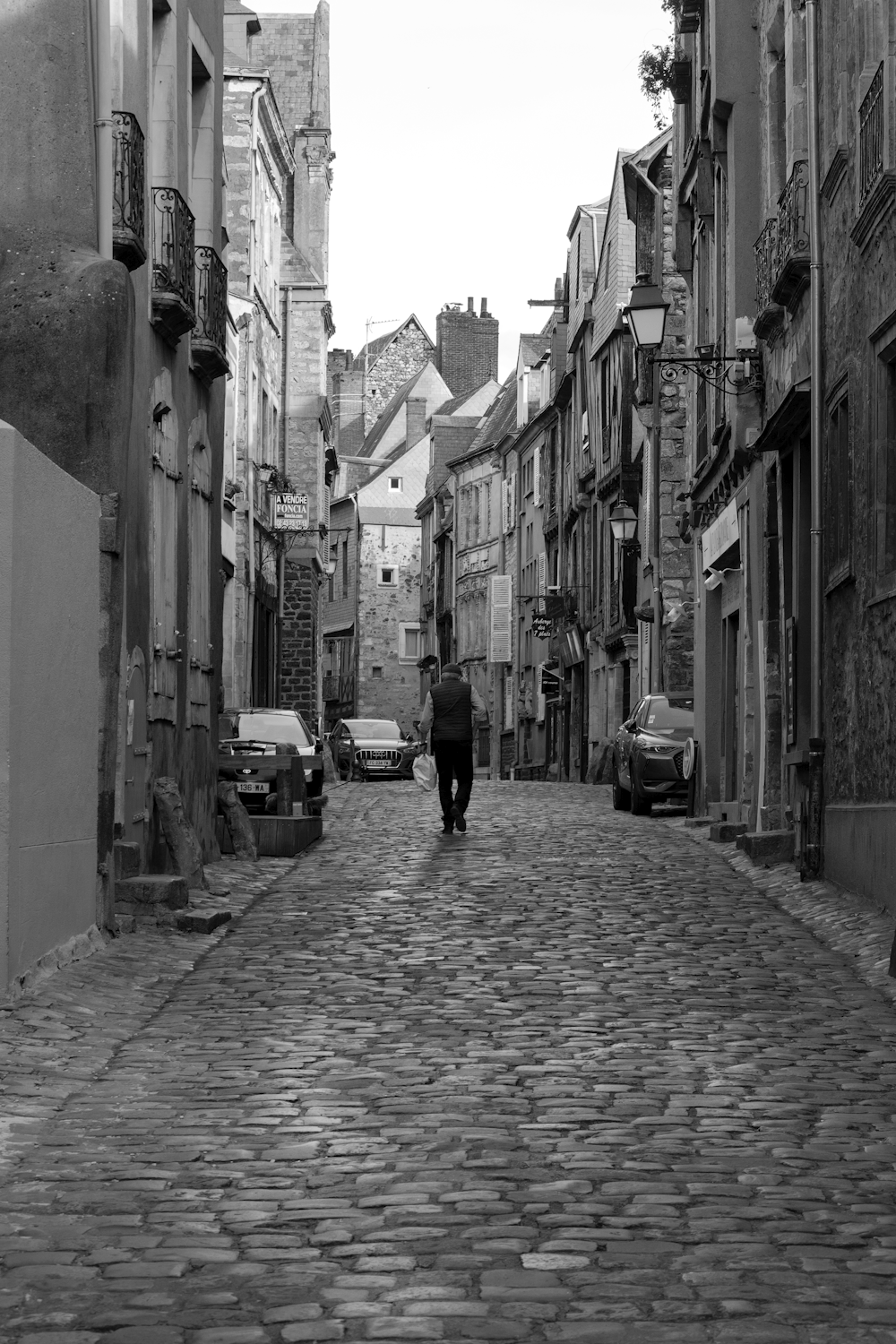 grayscale photo of man walking on street