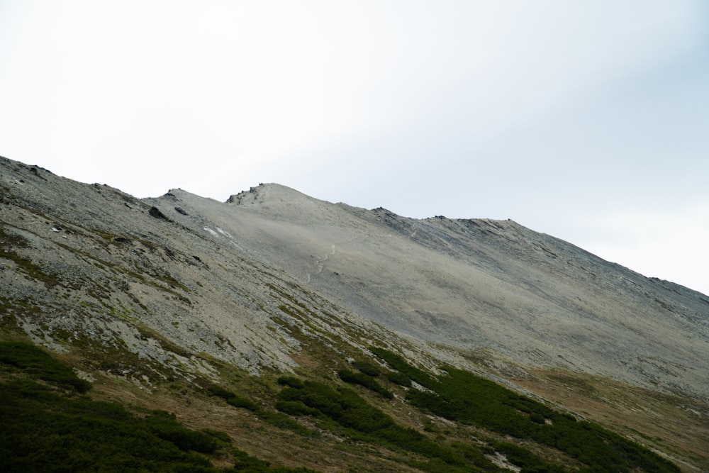 montagna verde e grigia sotto il cielo bianco durante il giorno