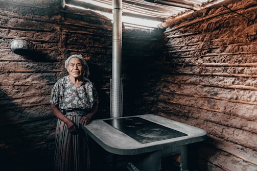 Researchers interviewing an elderly woman in traditional attire in a rustic village setting.