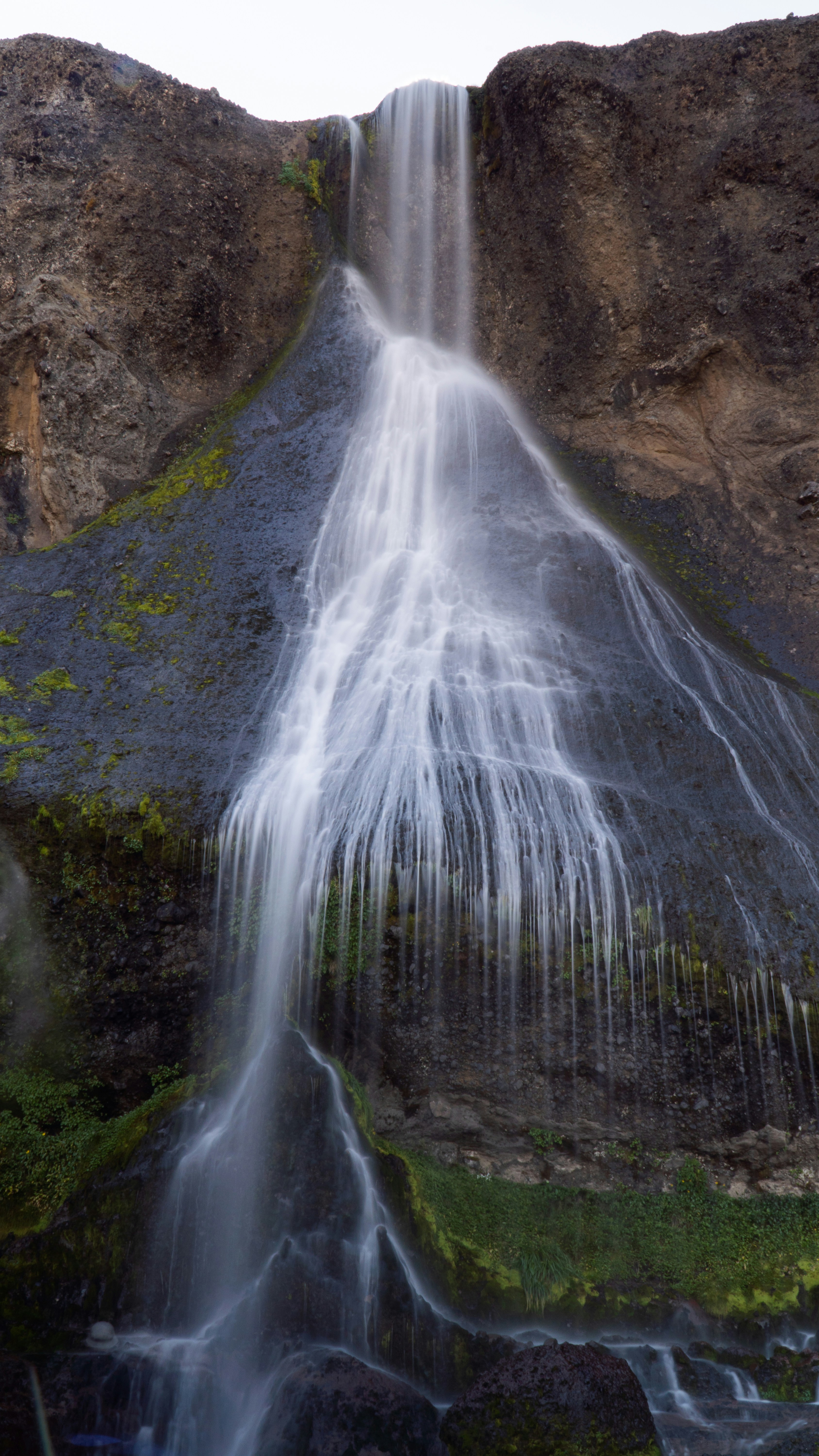 water falls on brown rocky mountain