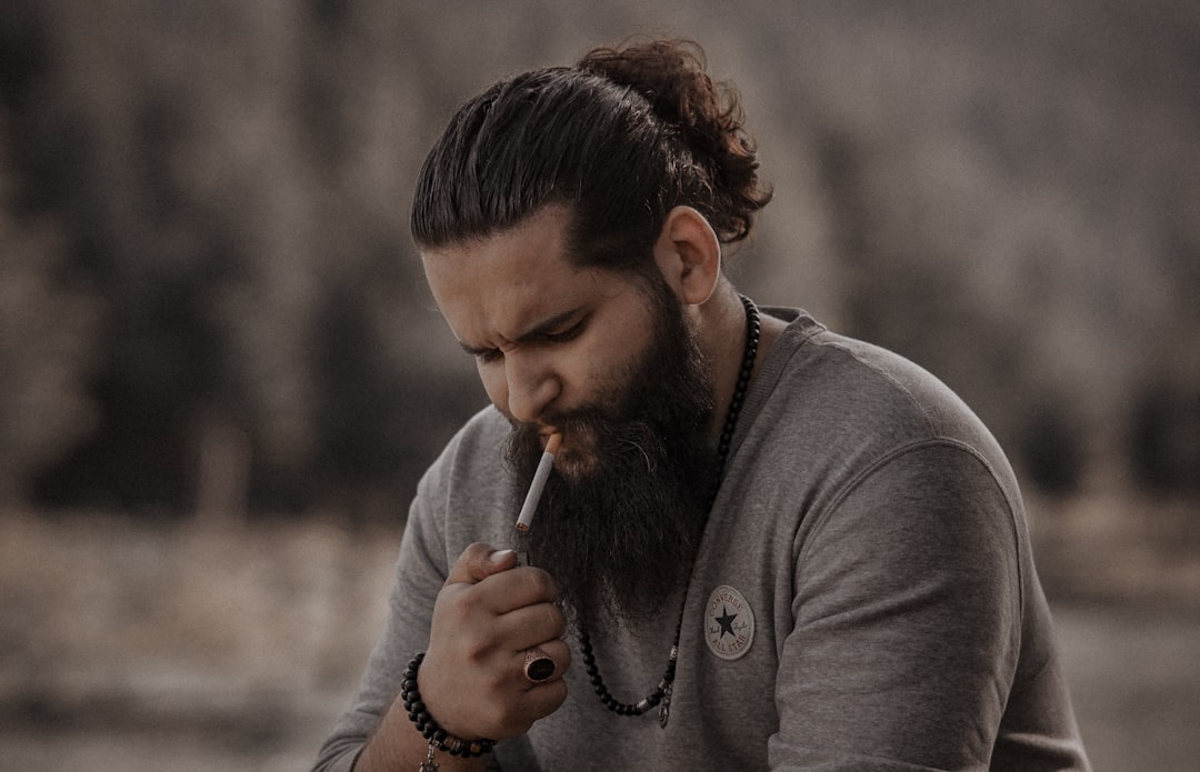 man in gray long sleeve shirt holding cigarette stick