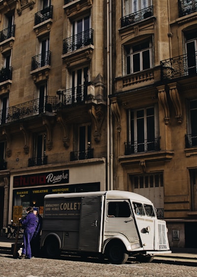 A sleek Valmo delivery van parked outside a modern office building at sunset.