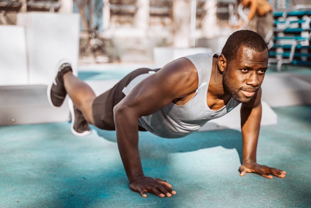 man in white tank top and gray shorts sitting on blue floor