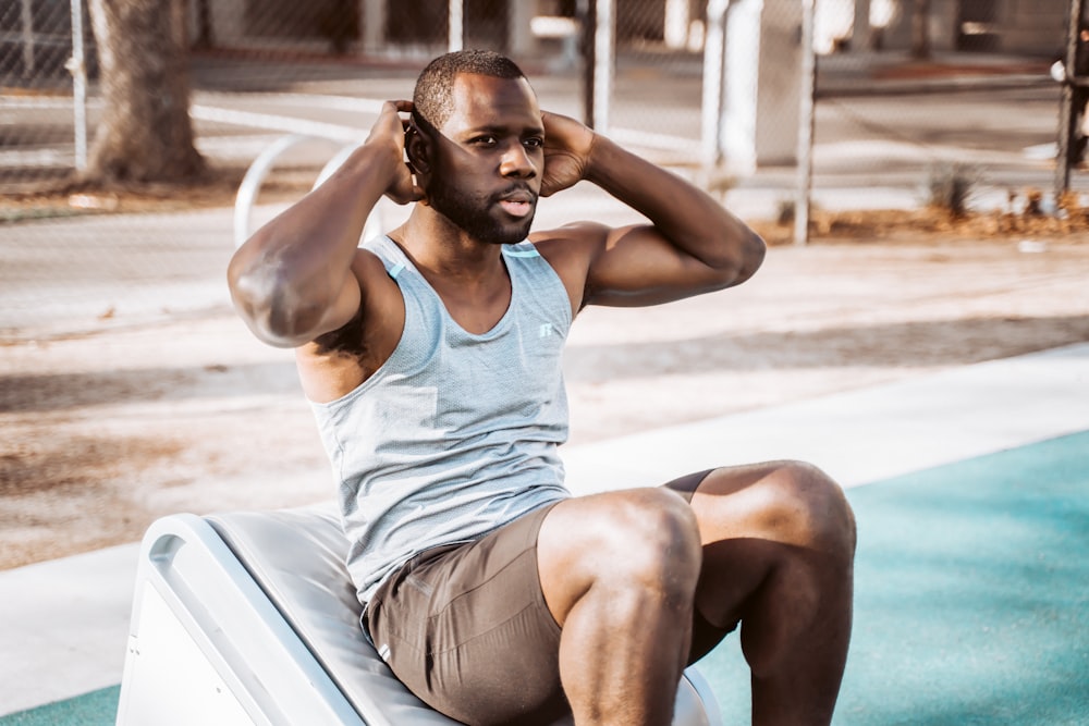 woman in white tank top and gray shorts sitting on white car