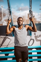 man in gray tank top holding blue and black basketball hoop