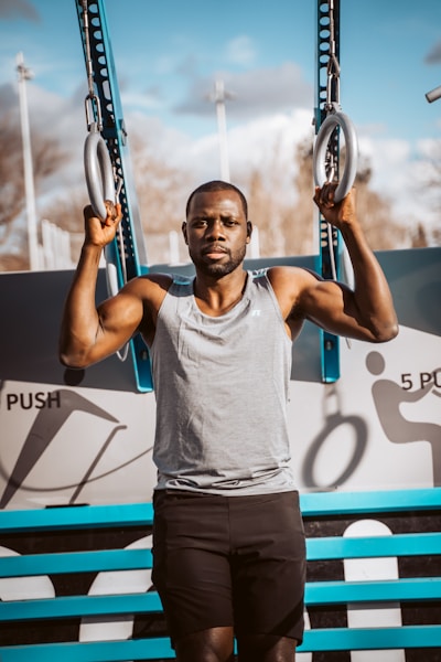 man in gray tank top holding blue and black basketball hoop