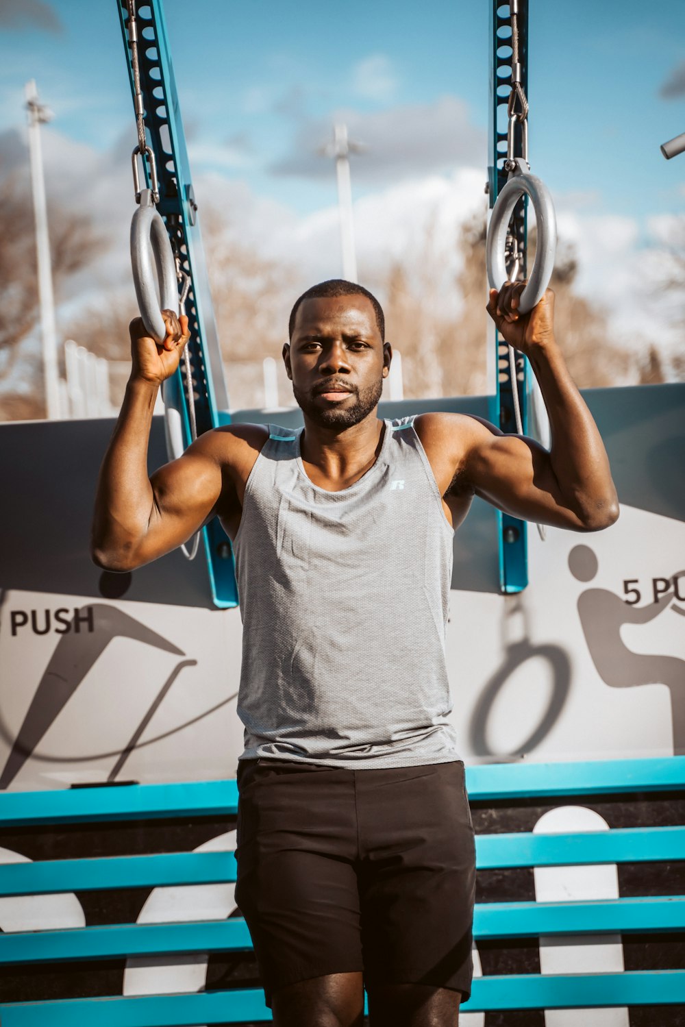 man in gray tank top holding blue and black basketball hoop