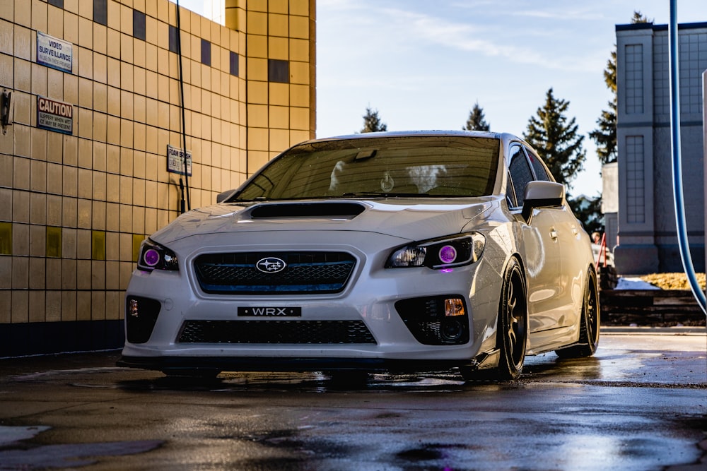 white honda car parked beside brown brick wall