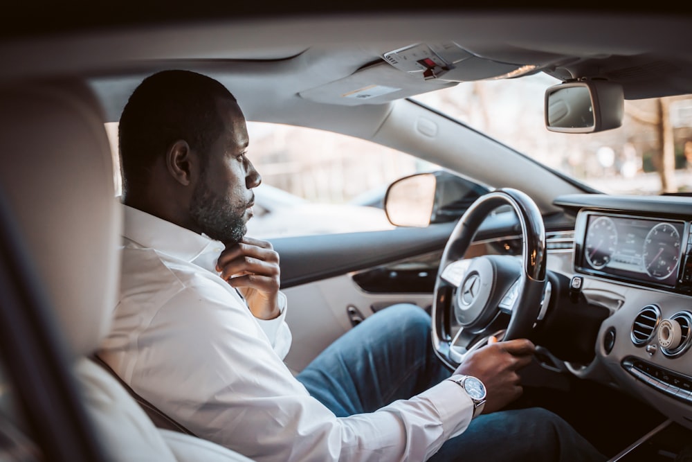 homme en chemise blanche conduisant une voiture pendant la journée