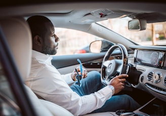 man in white dress shirt driving car during daytime