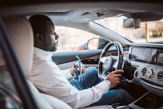 man in white dress shirt driving car during daytime