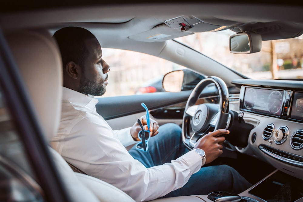 man in white dress shirt driving car during daytime