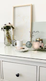 A minimalist vignette featuring rovance accessories arranged on a white wooden table with soft pink accents
