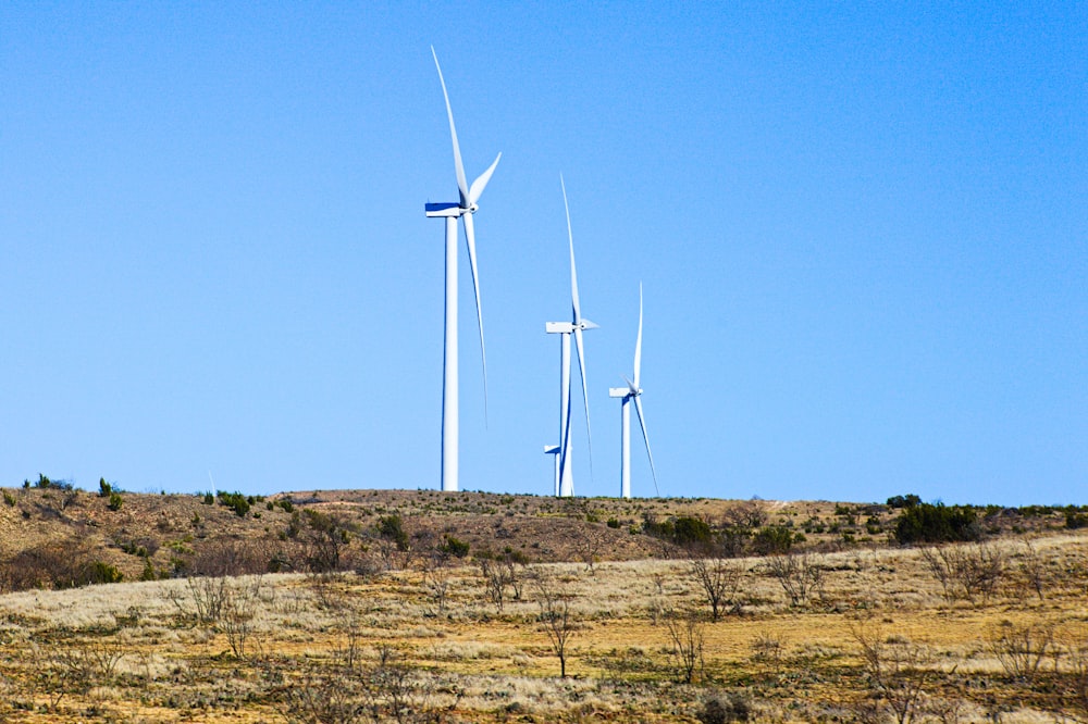 white wind turbines on brown field under blue sky during daytime