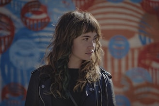 woman in black jacket standing near red and blue wall