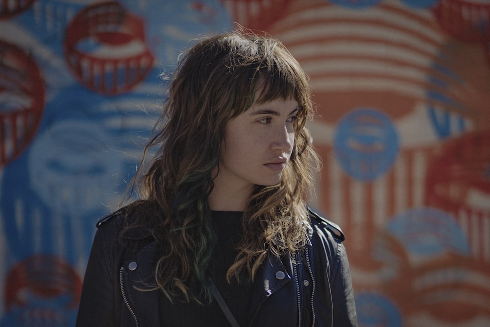 woman in black jacket standing near red and blue wall