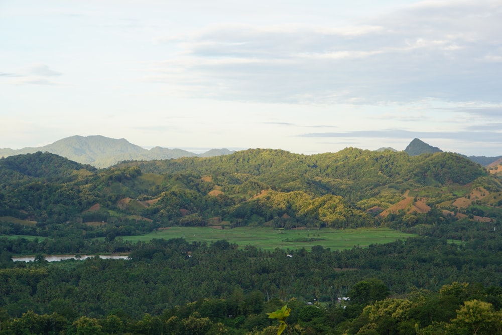 green trees and mountains under white clouds and blue sky during daytime