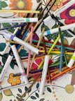 A collection of colorful, printable coloring book pages spread out on a wooden table.