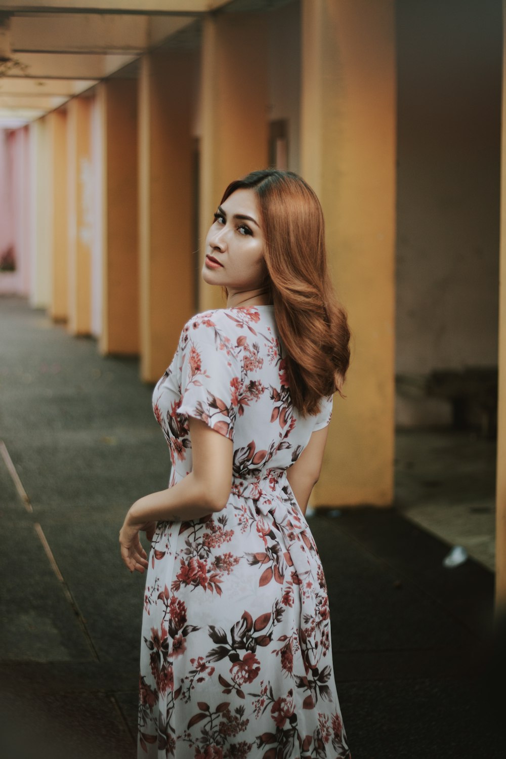 woman in white red and blue floral dress standing on sidewalk during daytime