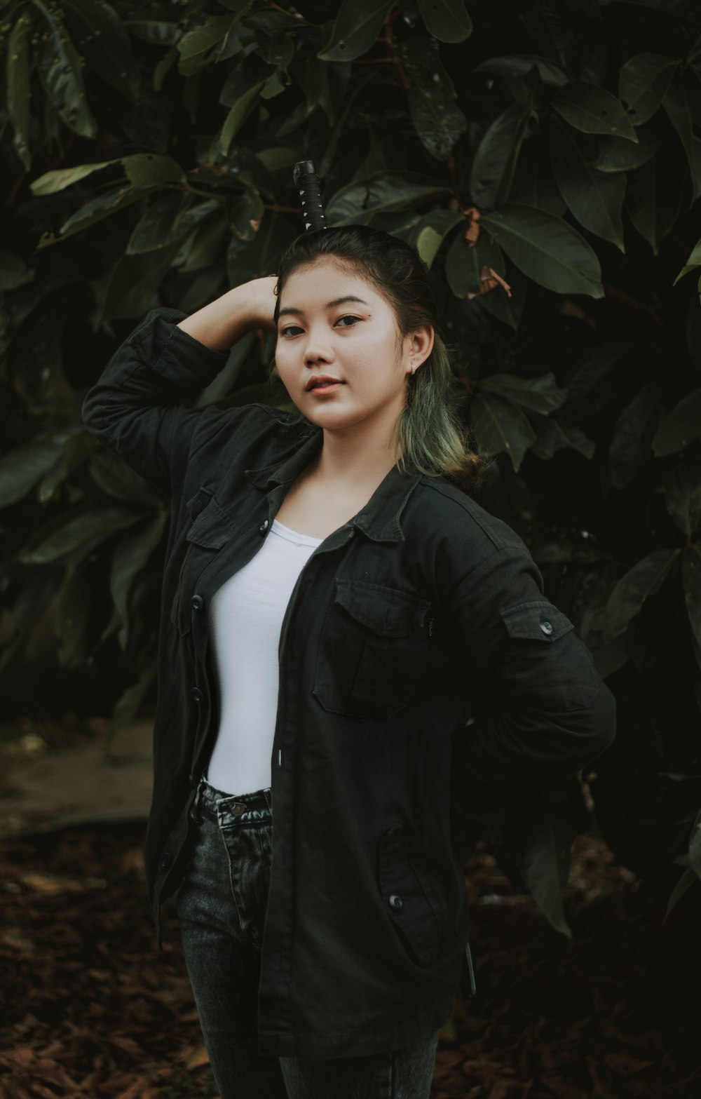 woman in black leather jacket standing near green plants during daytime