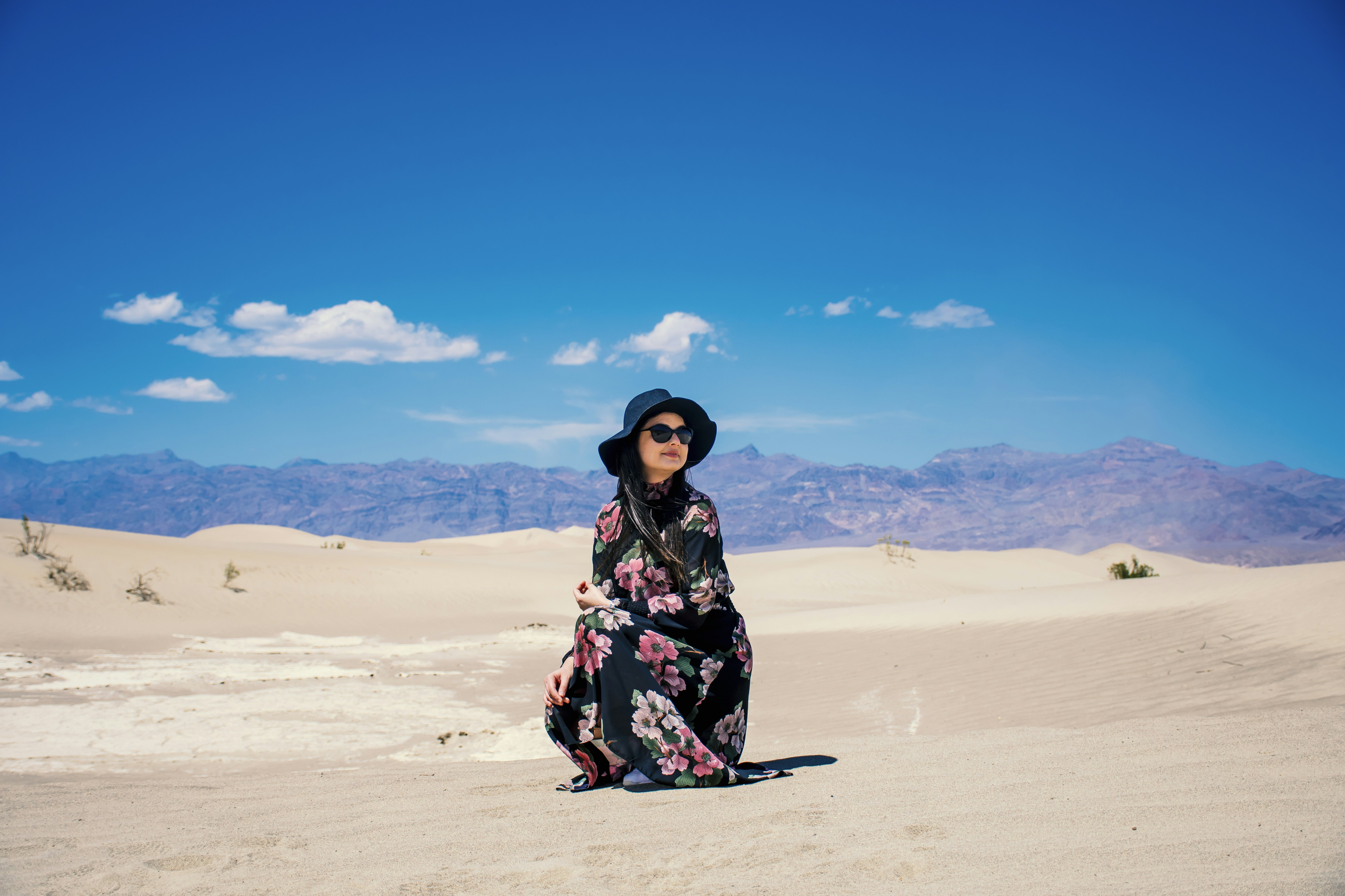 woman in black and red floral dress standing on white sand during daytime