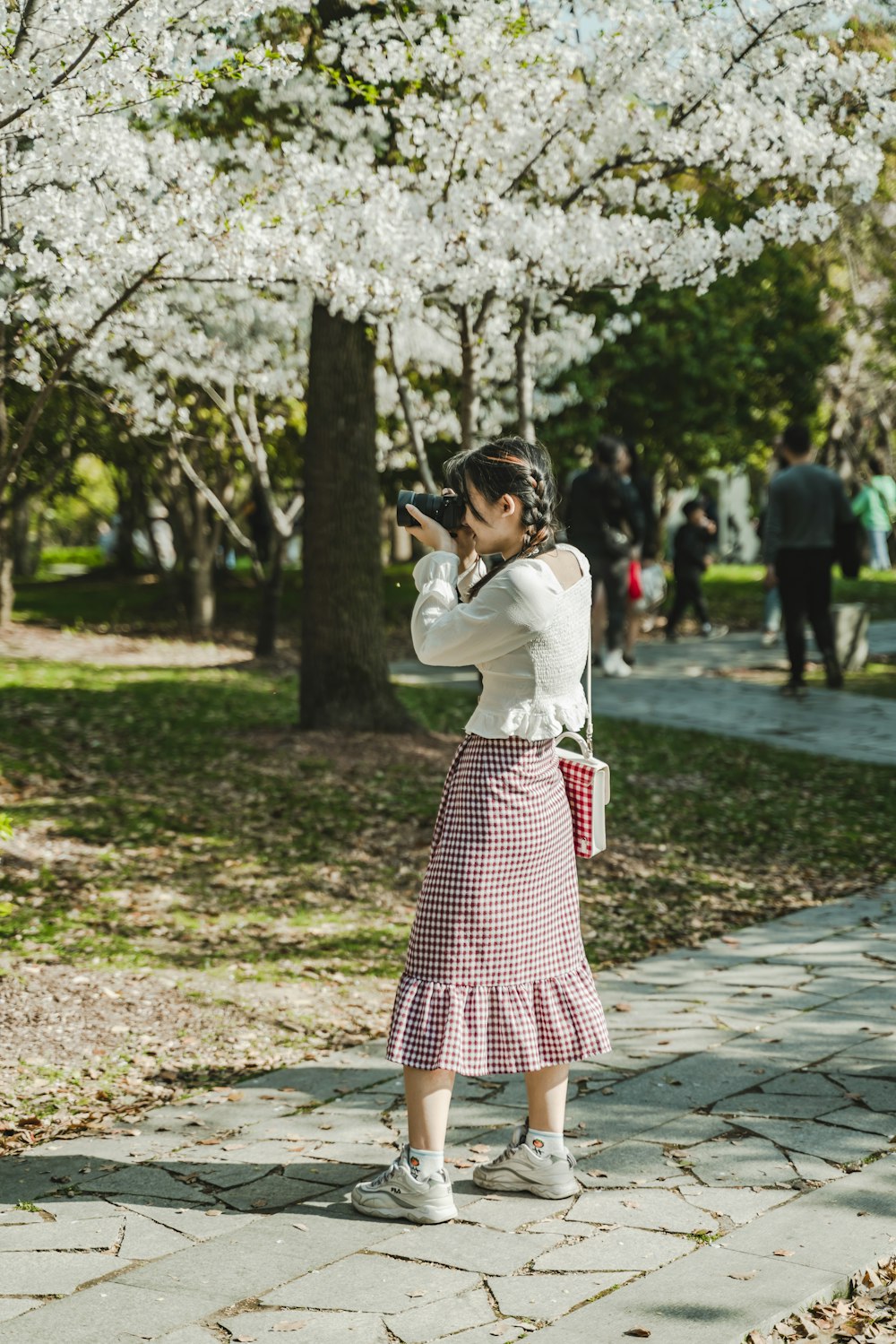 woman in white long sleeve shirt and pink and white polka dot skirt standing under white