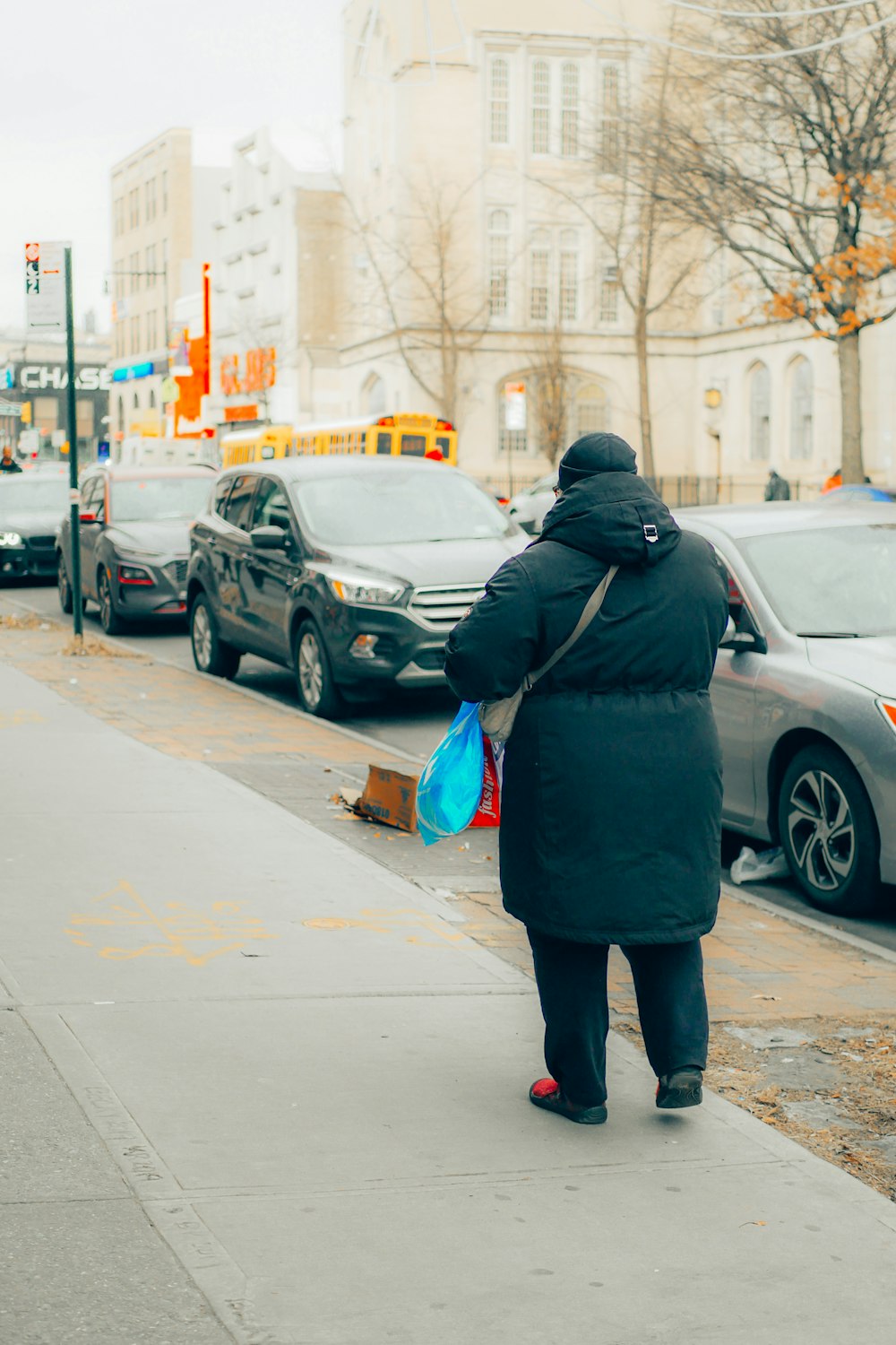 woman in black jacket and blue denim jeans walking on sidewalk during daytime