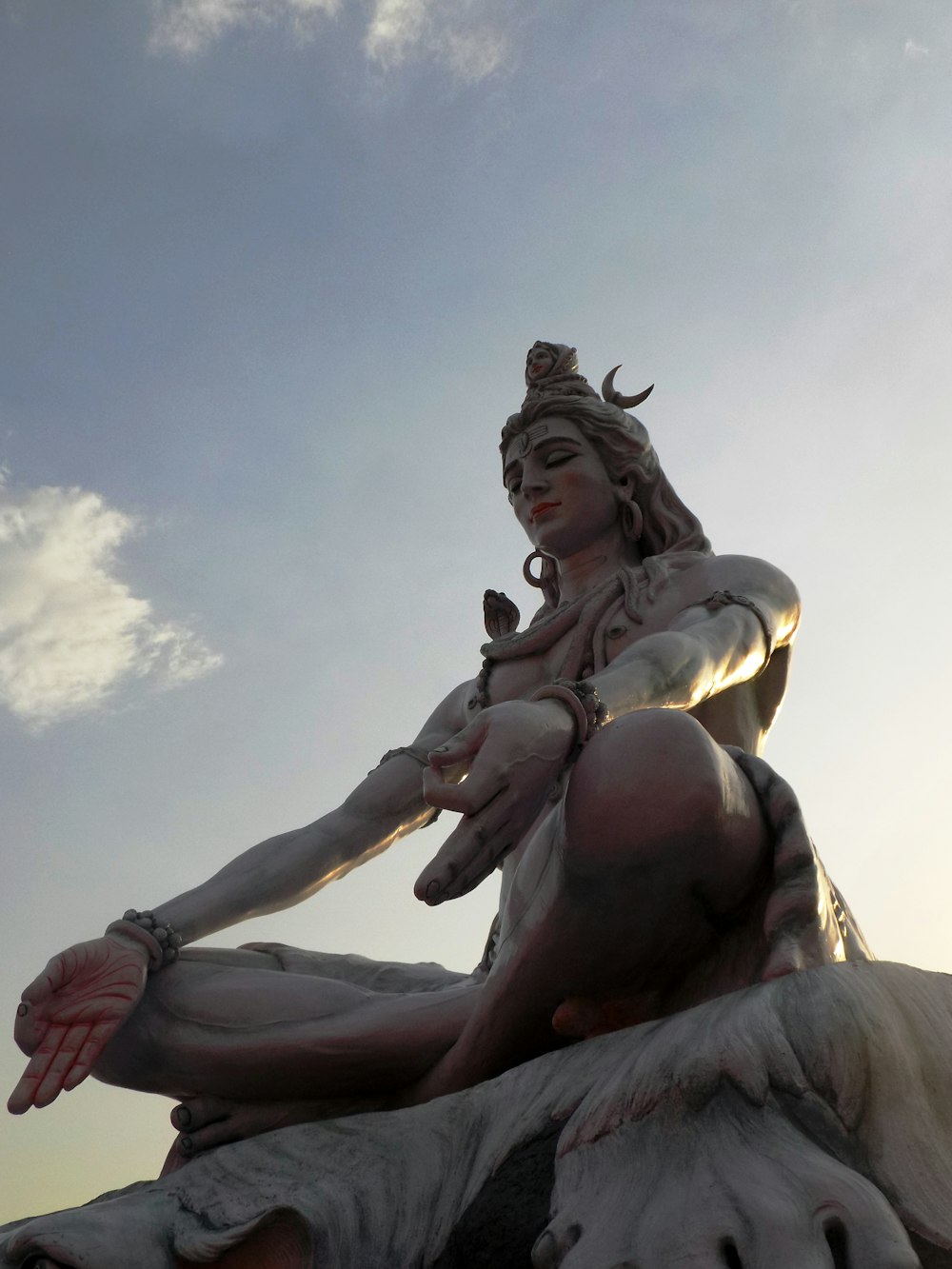 Mujer en estatua de vestido blanco bajo nubes blancas durante el día