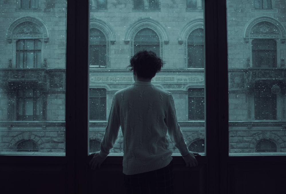 woman in white shirt standing in front of window