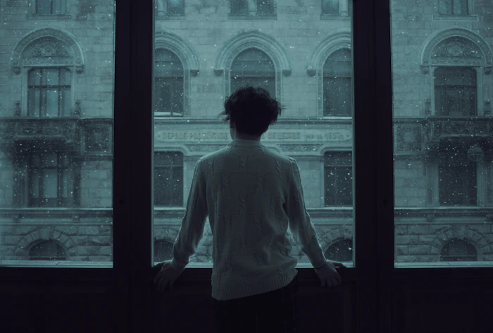 A woman in a quiet contemplative pause by a window