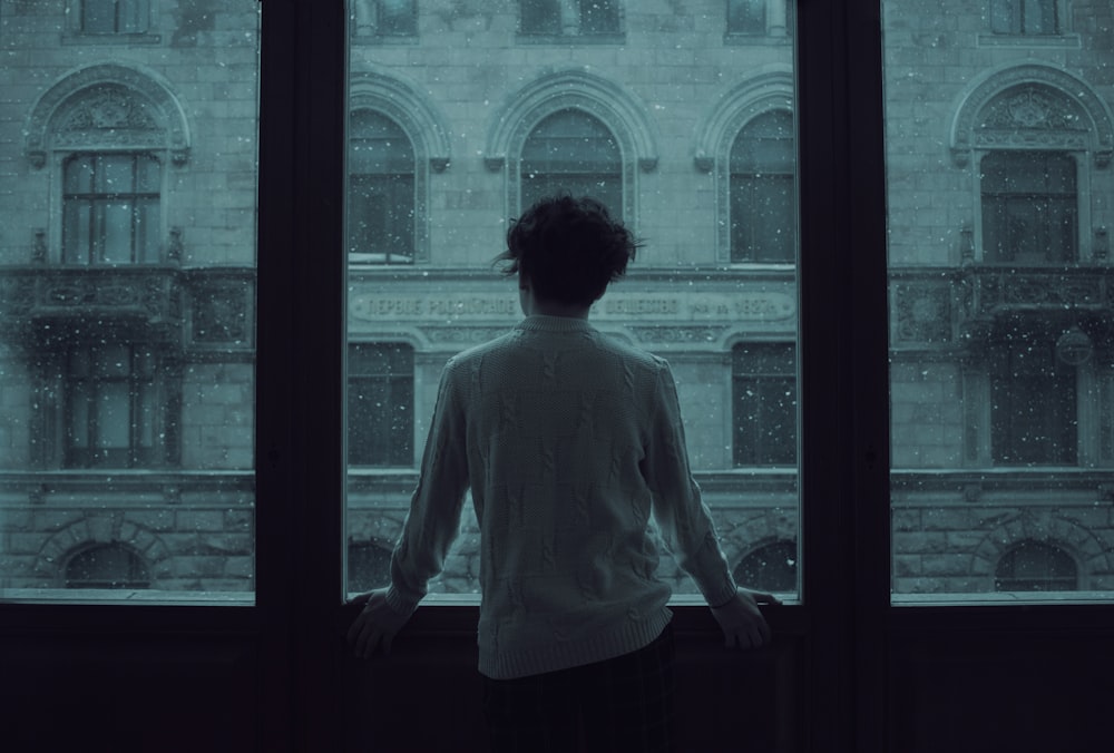 donna in camicia bianca in piedi davanti alla finestra