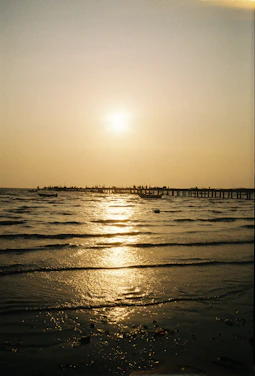 A warmly lit photo of a traveler gazing at a sunset over a serene beach, embodying peaceful adventure.