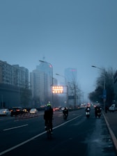 A vibrant cityscape at dusk with Vupe delivery riders on electric bikes navigating through traffic.