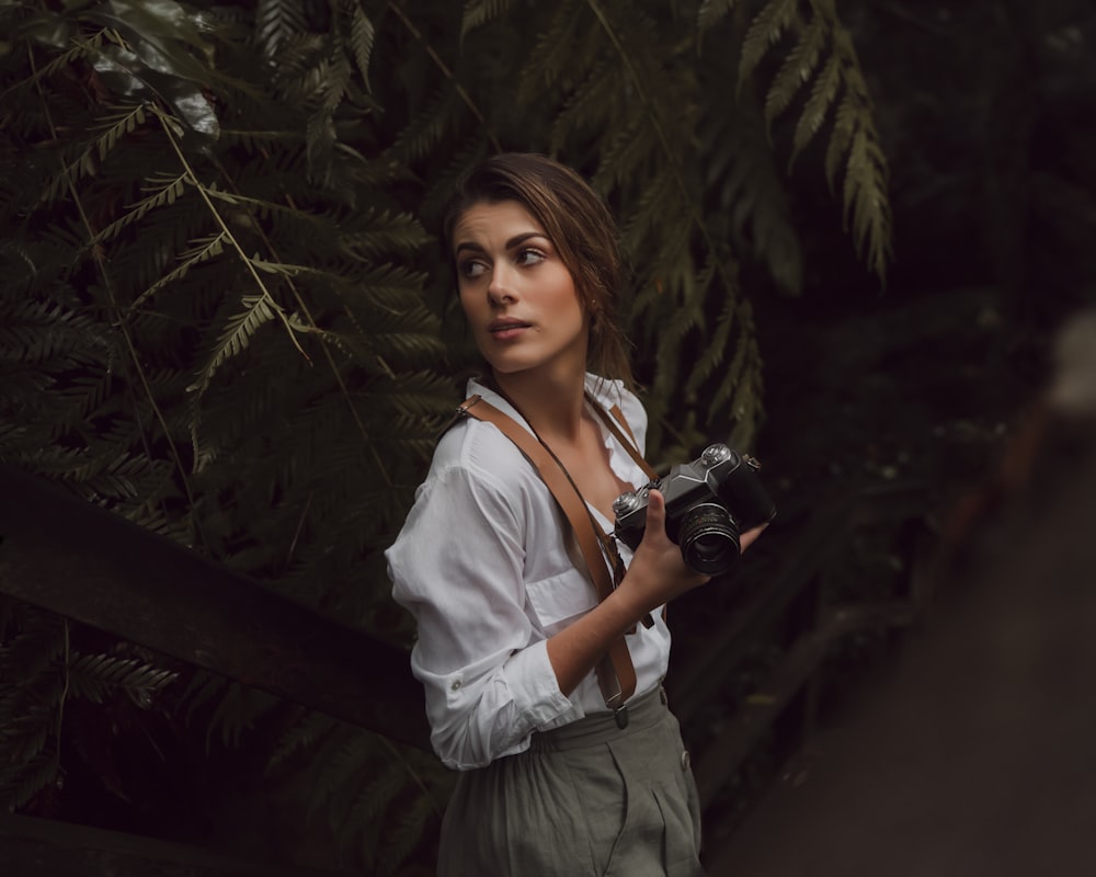 woman in white dress shirt holding black dslr camera