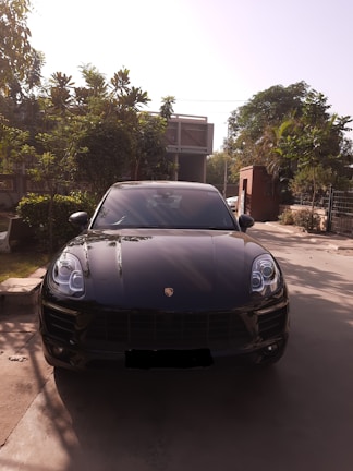 A spacious SUV with tinted windows waiting curbside, surrounded by lush greenery.