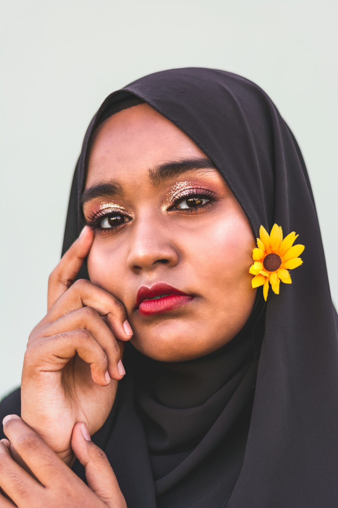 woman in black hijab holding sunflower