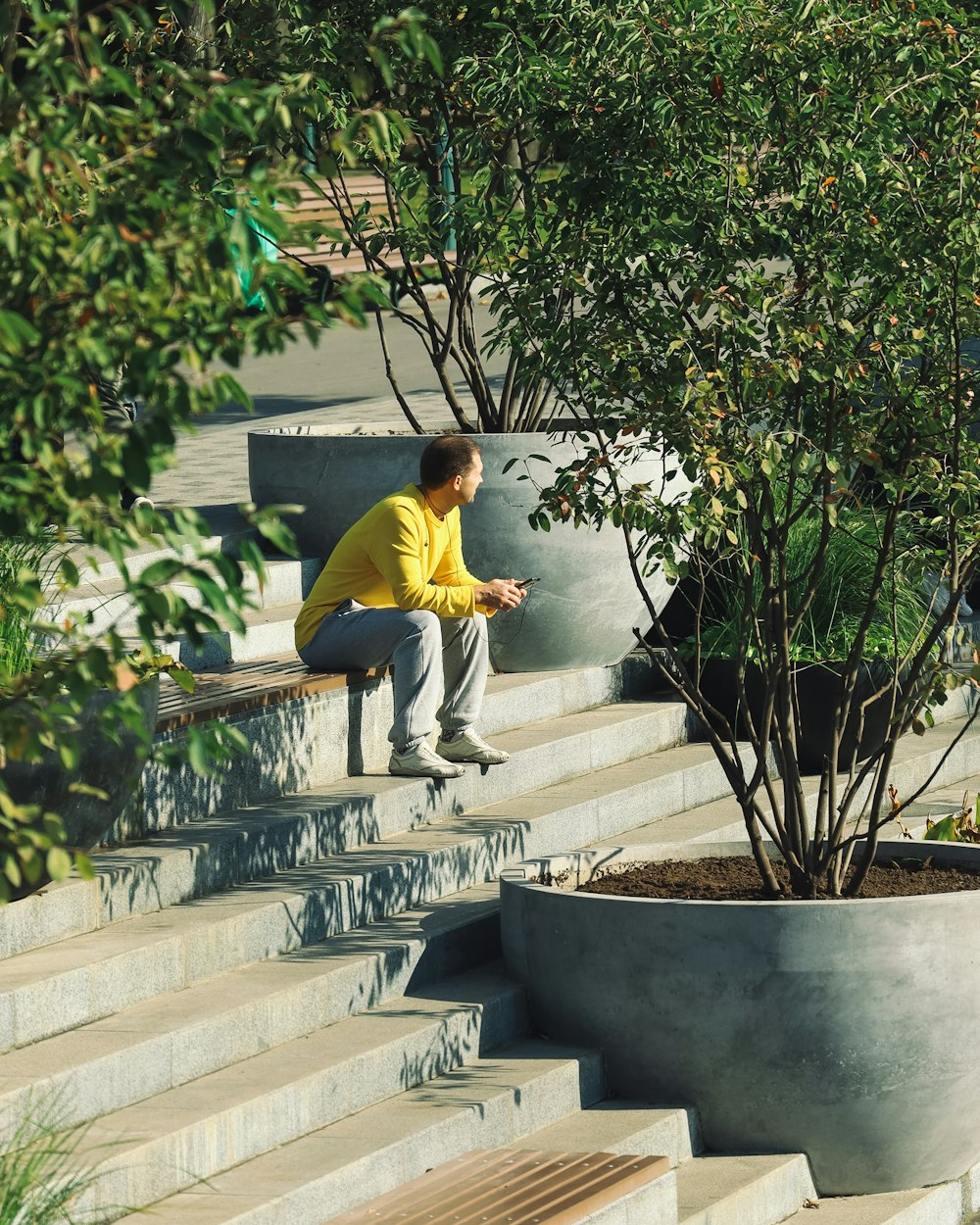 man in yellow shirt sitting on concrete staircase