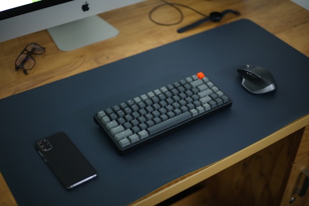A sleek, minimalist desk setup featuring a smart notebook, wireless keyboard, and a small digital timer glowing softly in blue.