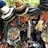A vibrant display of assorted items, including neatly stacked hats of various materials and colors, colorful alphabet beads, decorative hair accessories, jewelry, and fabric belts. The collection appears densely packed and visually stimulating, likely part of a market stall.