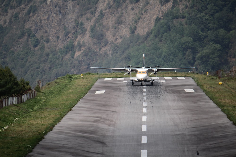 낮 동안 회색 아스팔트 도로에 흰색과 노란색 비행기