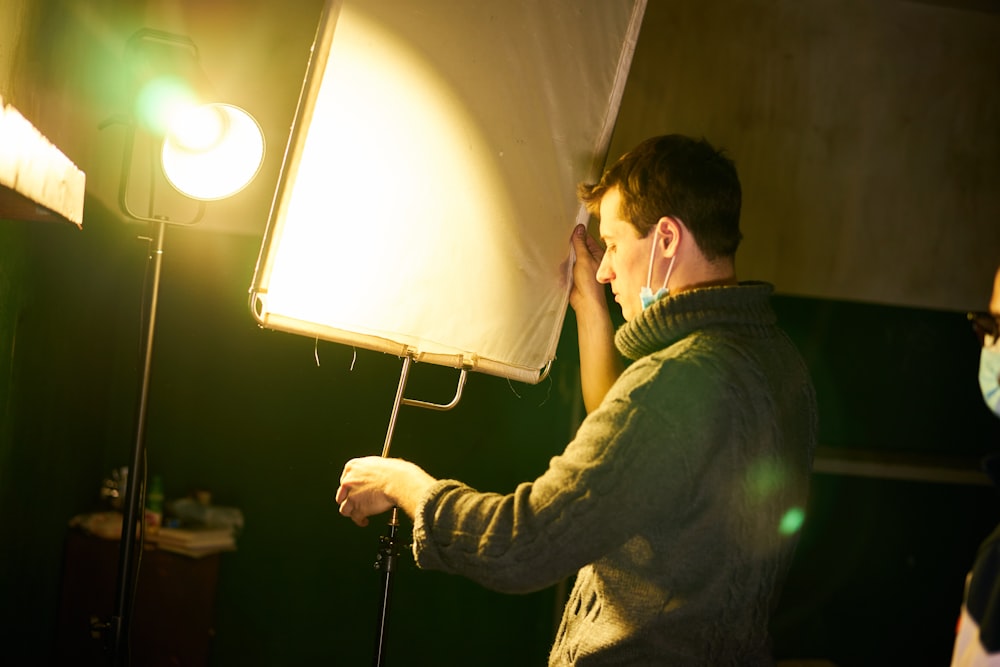 man in black jacket holding white and black floor lamp