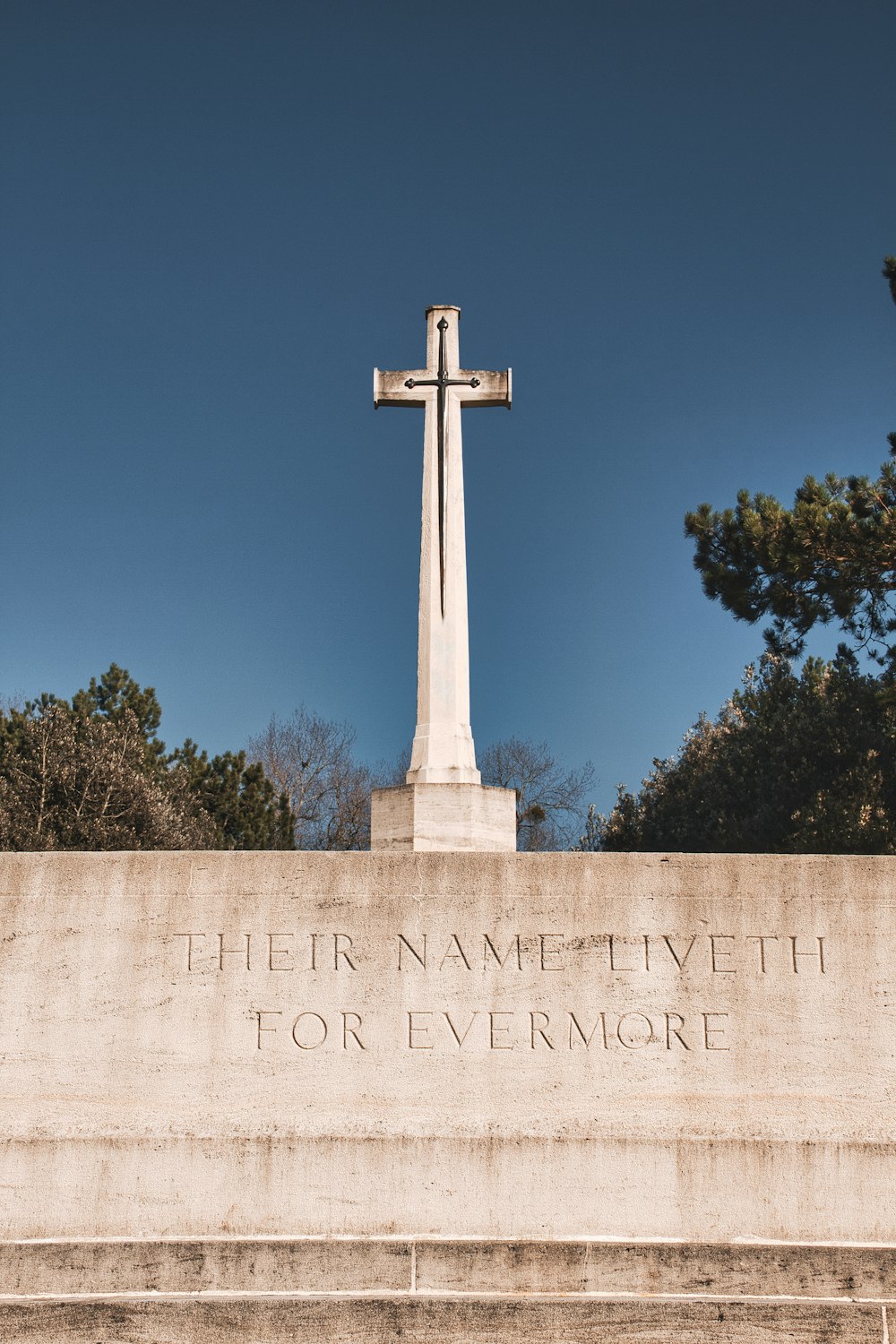 white cross monument near green trees during daytime