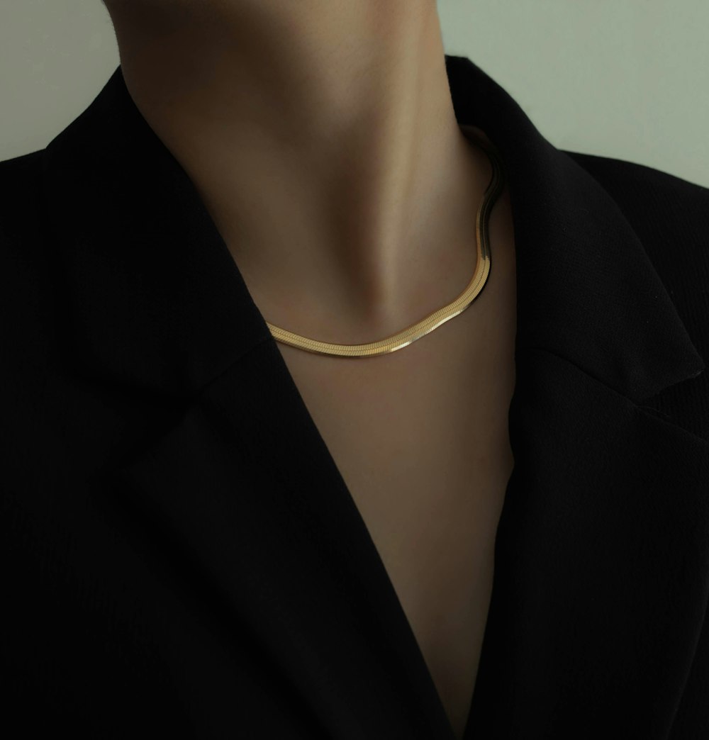 donna in blazer nero che indossa collana d'oro