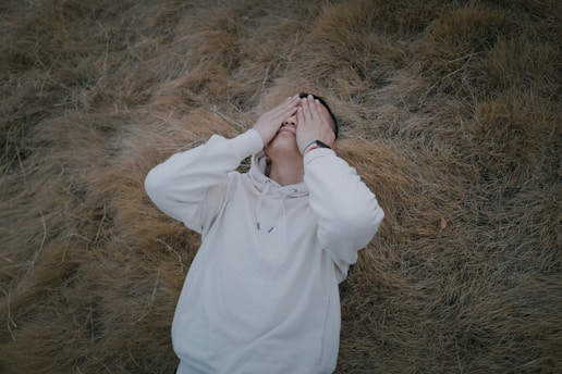 woman in white coat covering her face with her hands