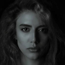 A close-up portrait of a person with expressive eyes against a simple background.