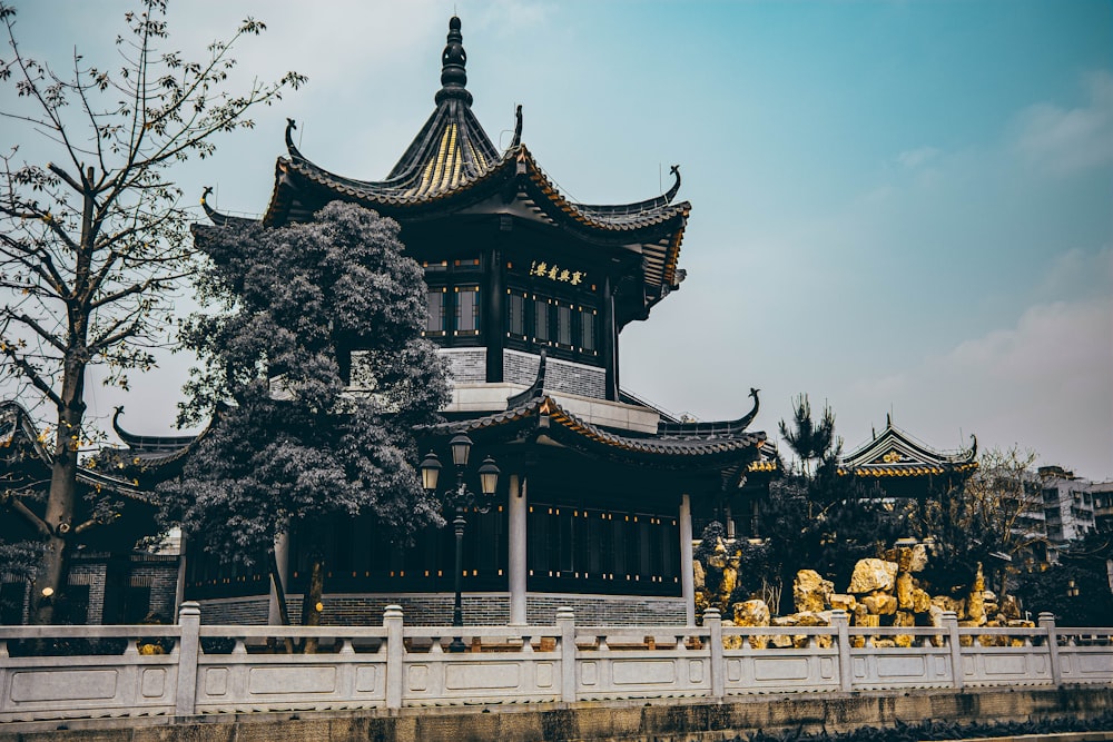 昼間の緑の木々の近くの黒と白の寺院