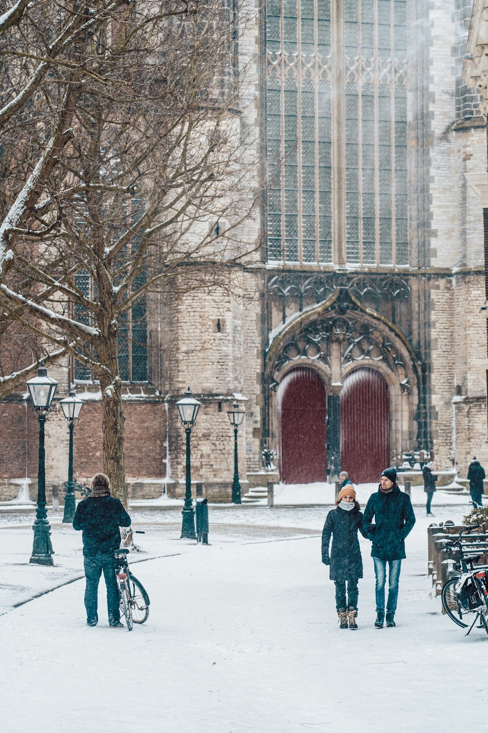 people walking on snow covered ground near brown building during daytime