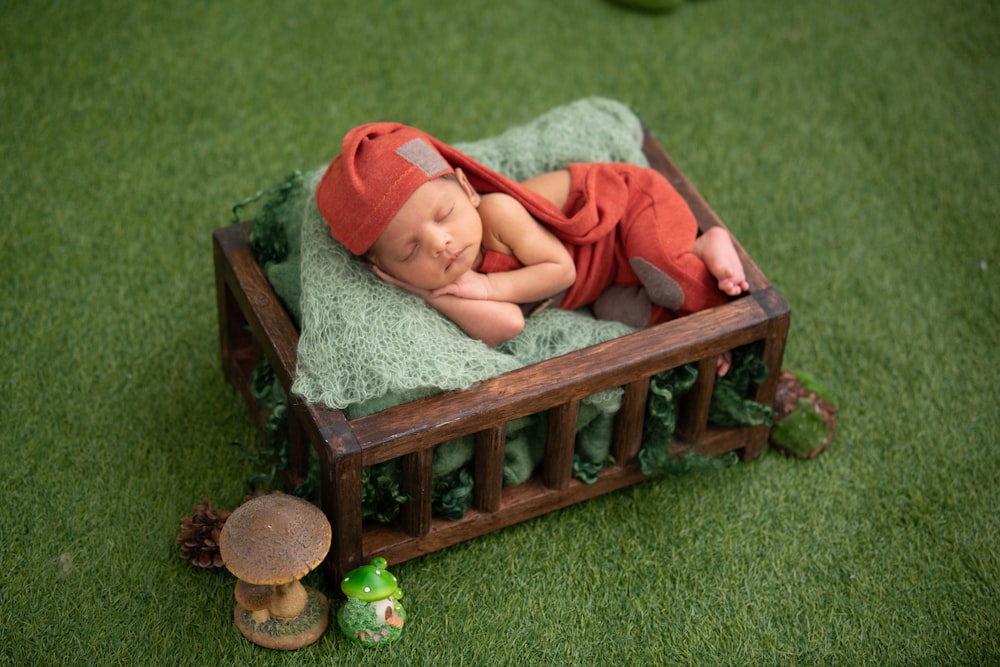 baby in red and white stripe onesie lying on brown wooden bed