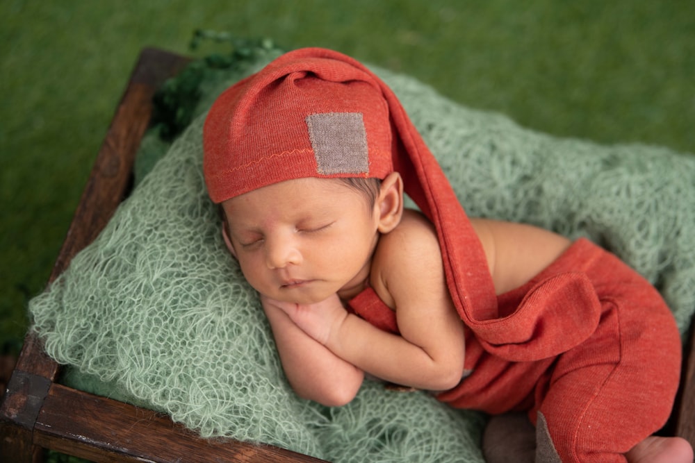 bambino in berretto a maglia rosso sdraiato su tessuto grigio
