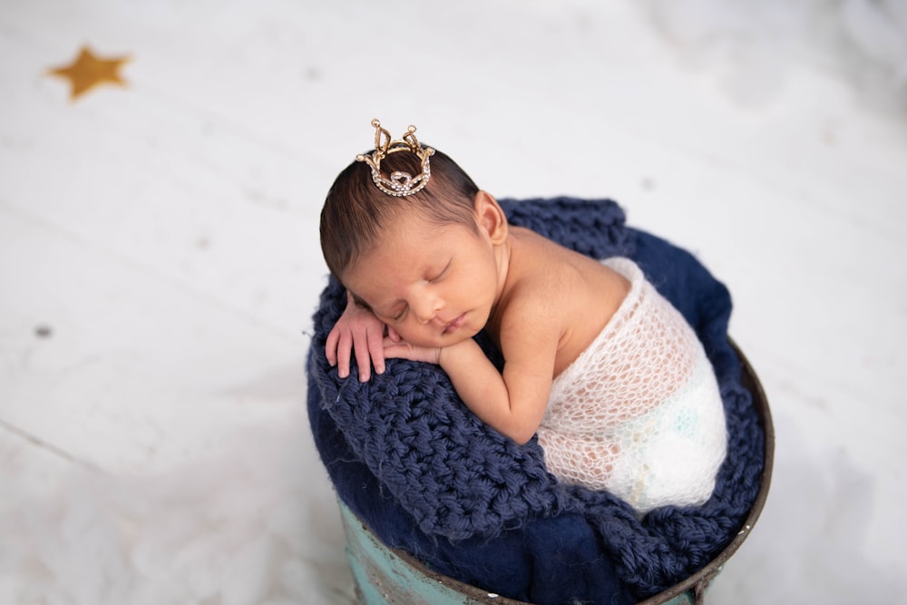 baby in white tank top lying on blue textile